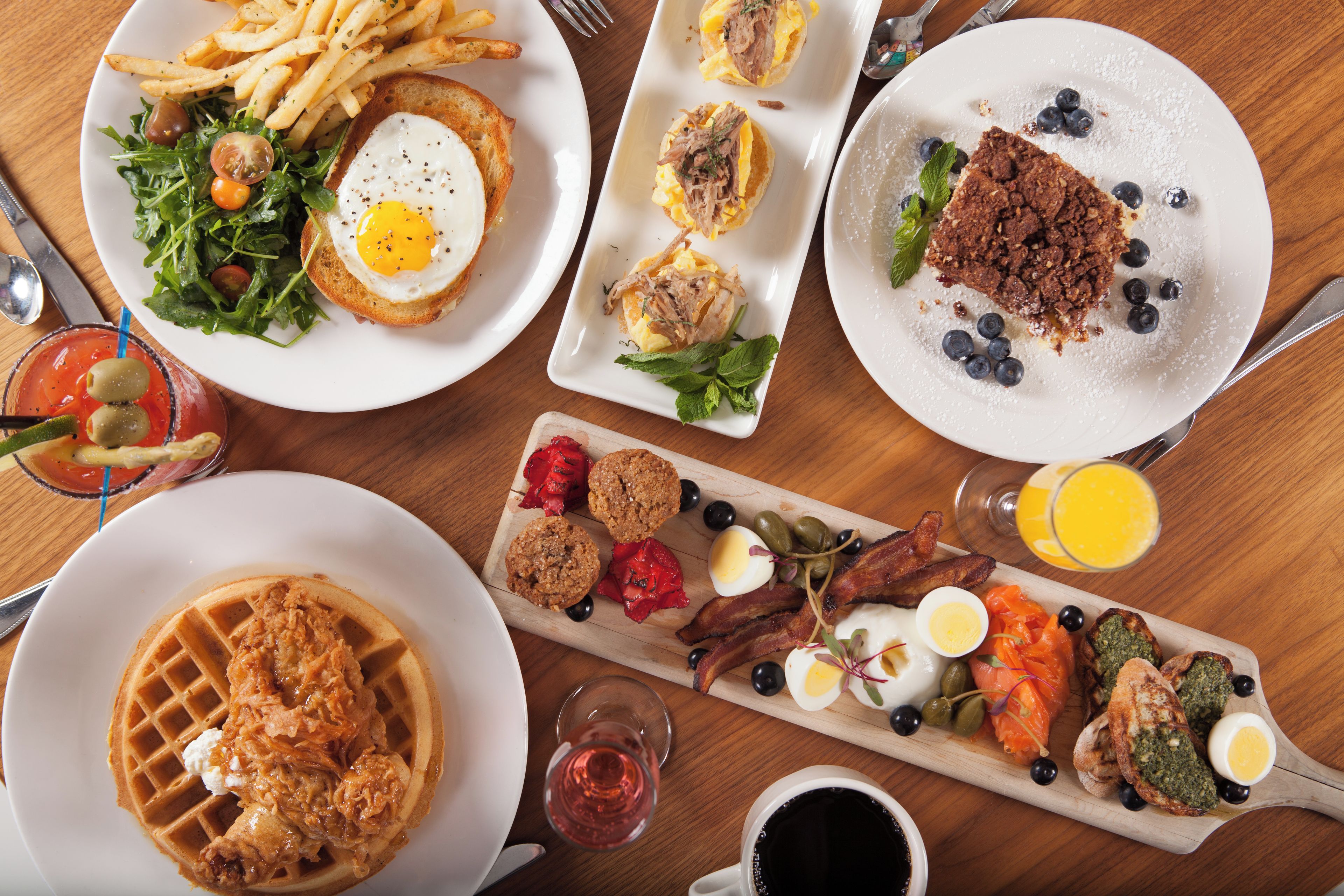 Ein reichhaltiges Frühstücksbuffet mit verschiedenen Speisen, darunter Waffeln, Eier und Fleischwaren.