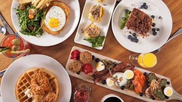 Ein reichhaltiges Frühstücksbuffet mit verschiedenen Speisen, darunter Waffeln, Eier und Fleischwaren.
