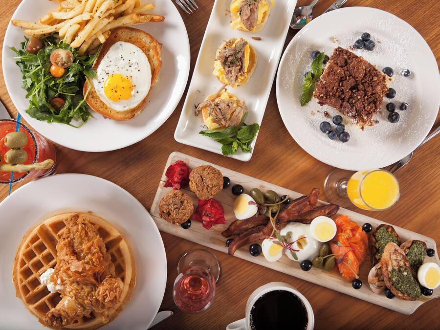 Ein reichhaltiges Frühstücksbuffet mit verschiedenen Speisen, darunter Waffeln, Eier und Fleischwaren.