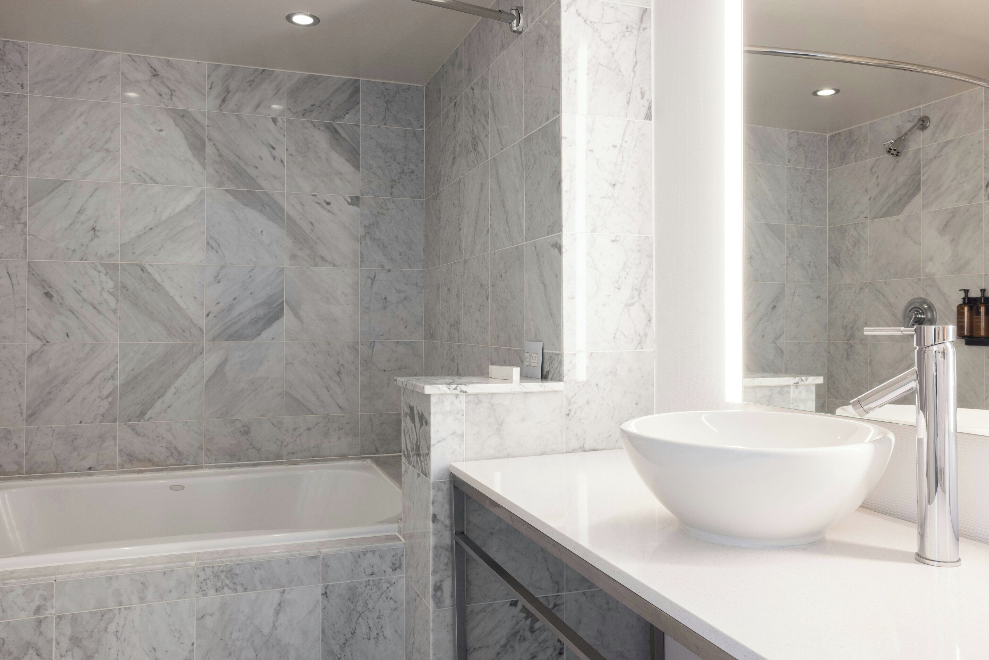 A modern bathroom with a large bathtub, a vessel sink, and a mirror.