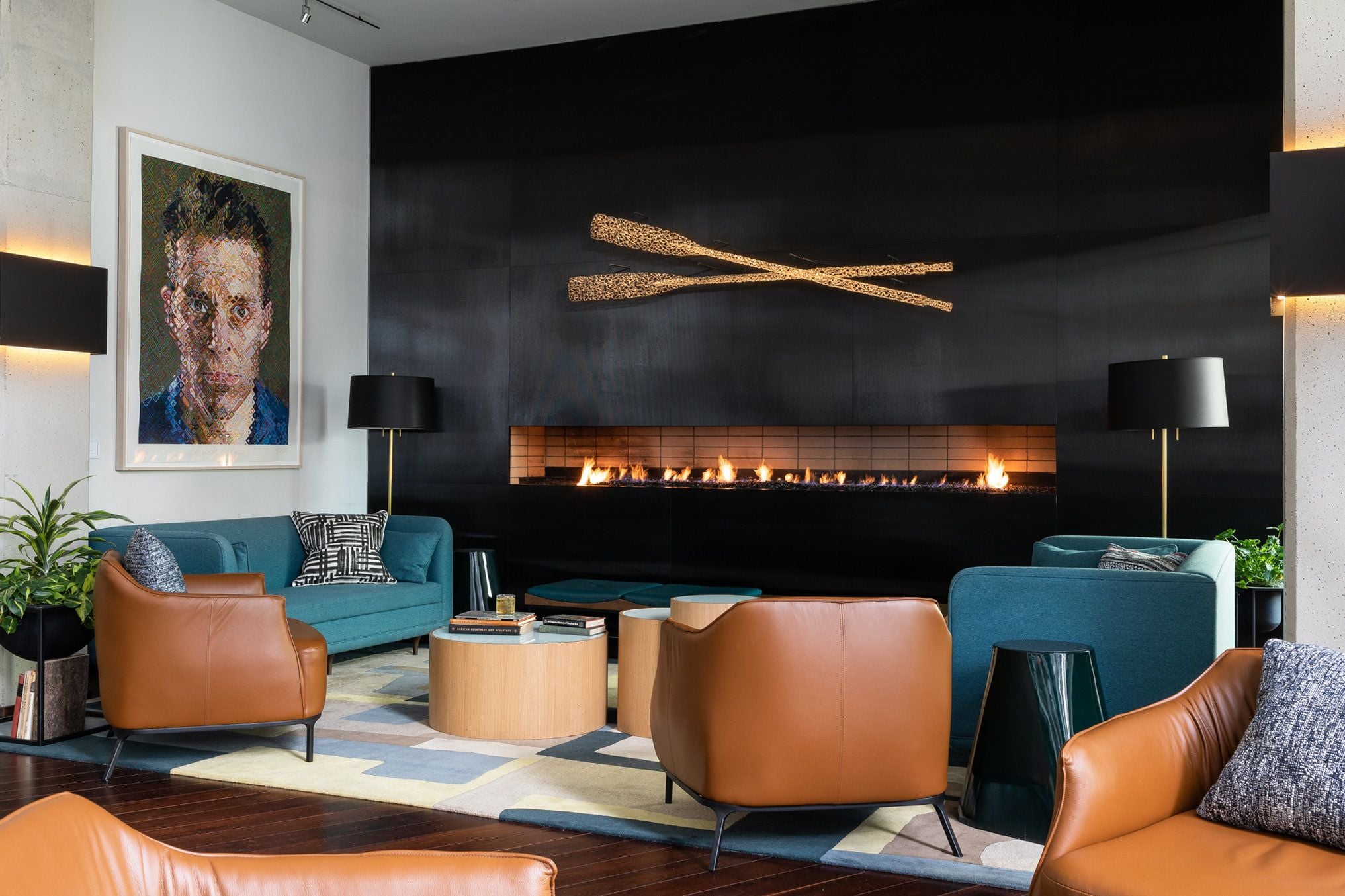 Una sala de estar moderna con chimenea, sofás de cuero y un cuadro grande en la pared.