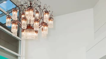 A reception desk with a chandelier, a television mounted on the wall, and a display of products.