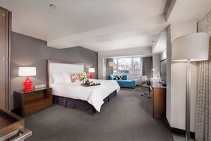 Ein Hotelzimmer mit Bett, Schreibtisch, Stuhl und Blick auf die Stadt.