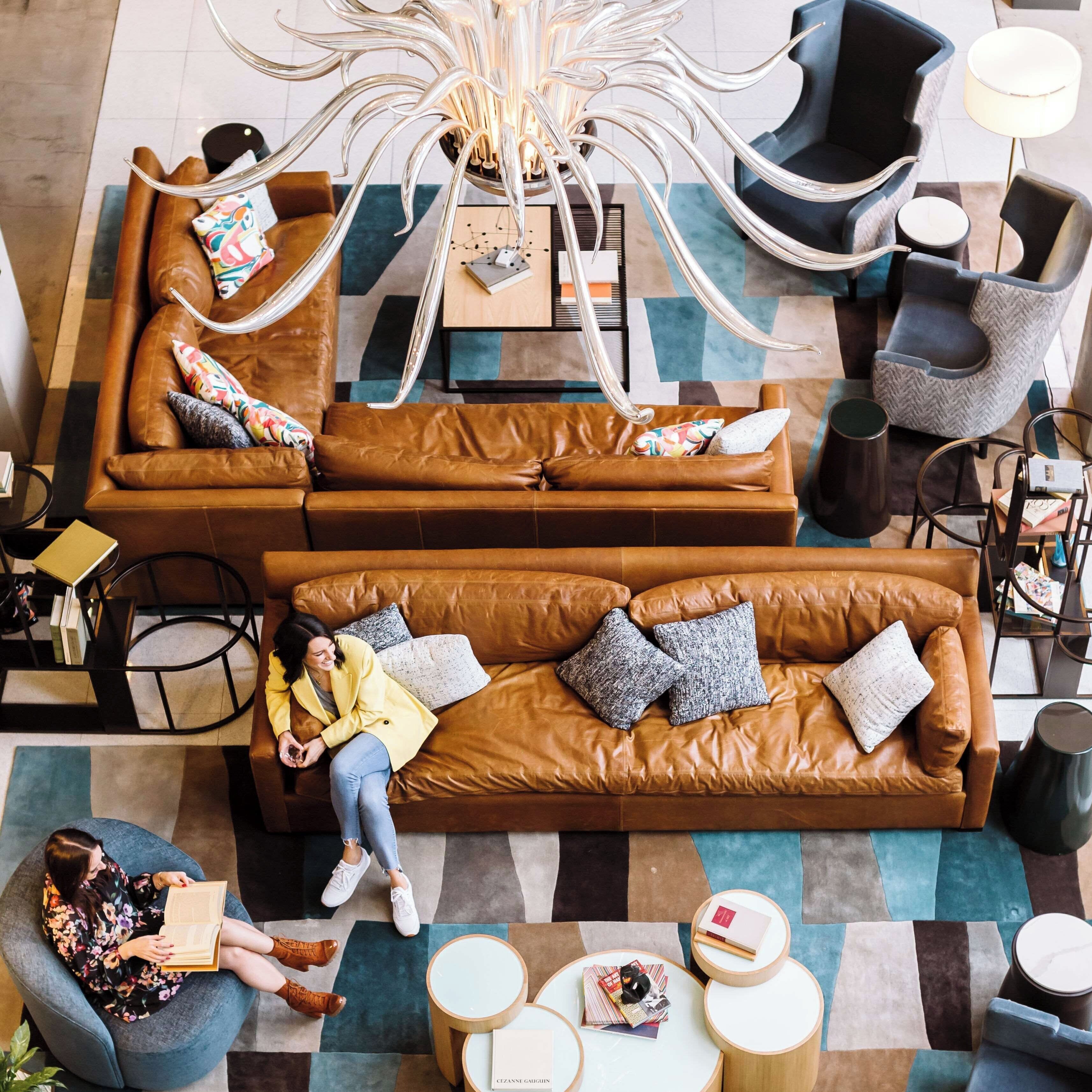 A modern lounge area with leather sofas, a central coffee table, and a unique chandelier.
