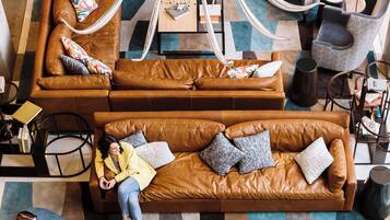 A modern lounge area with leather sofas, a central coffee table, and a unique chandelier.