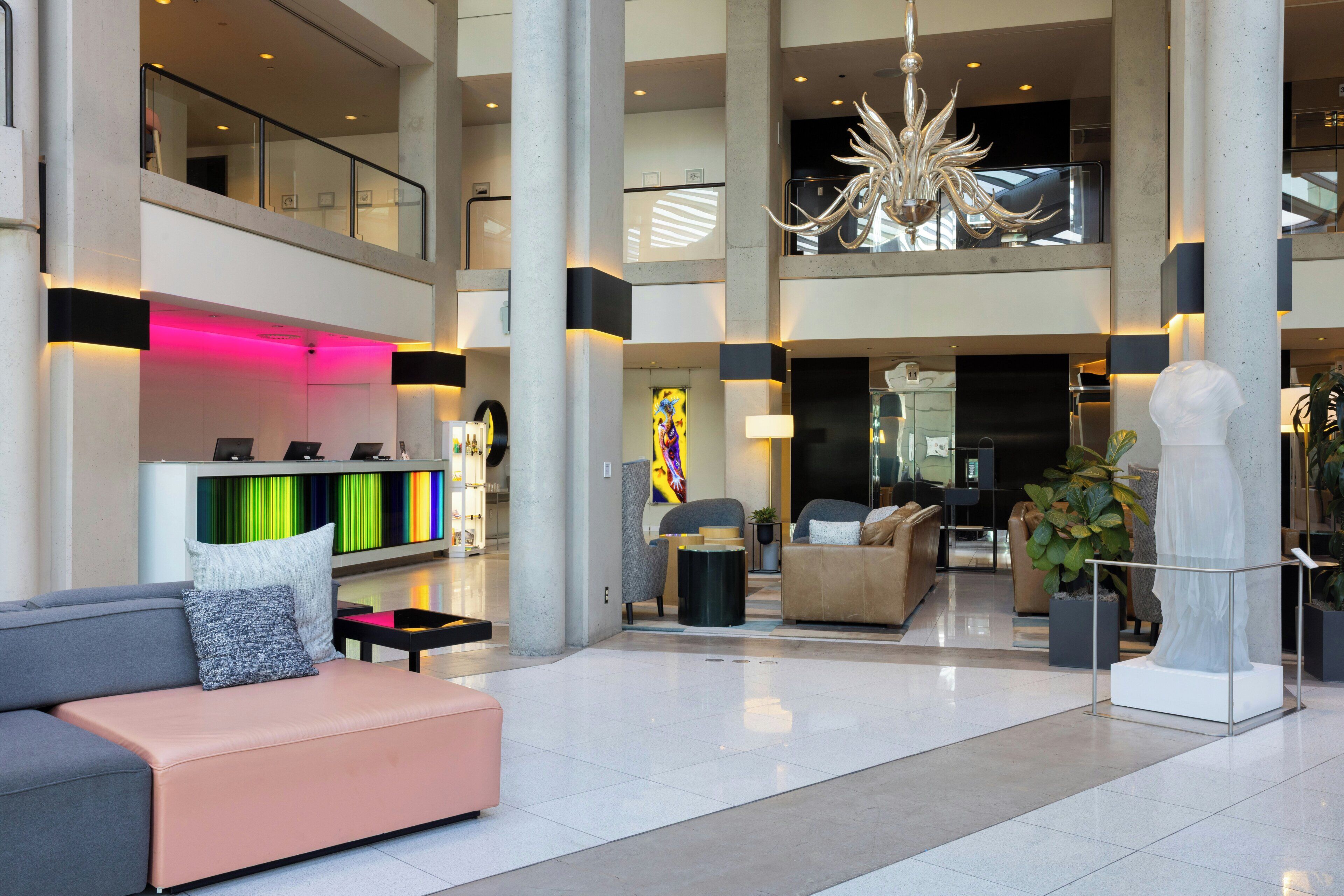 A spacious lobby with a high ceiling, a modern chandelier, and a seating area with a sofa and armchairs.