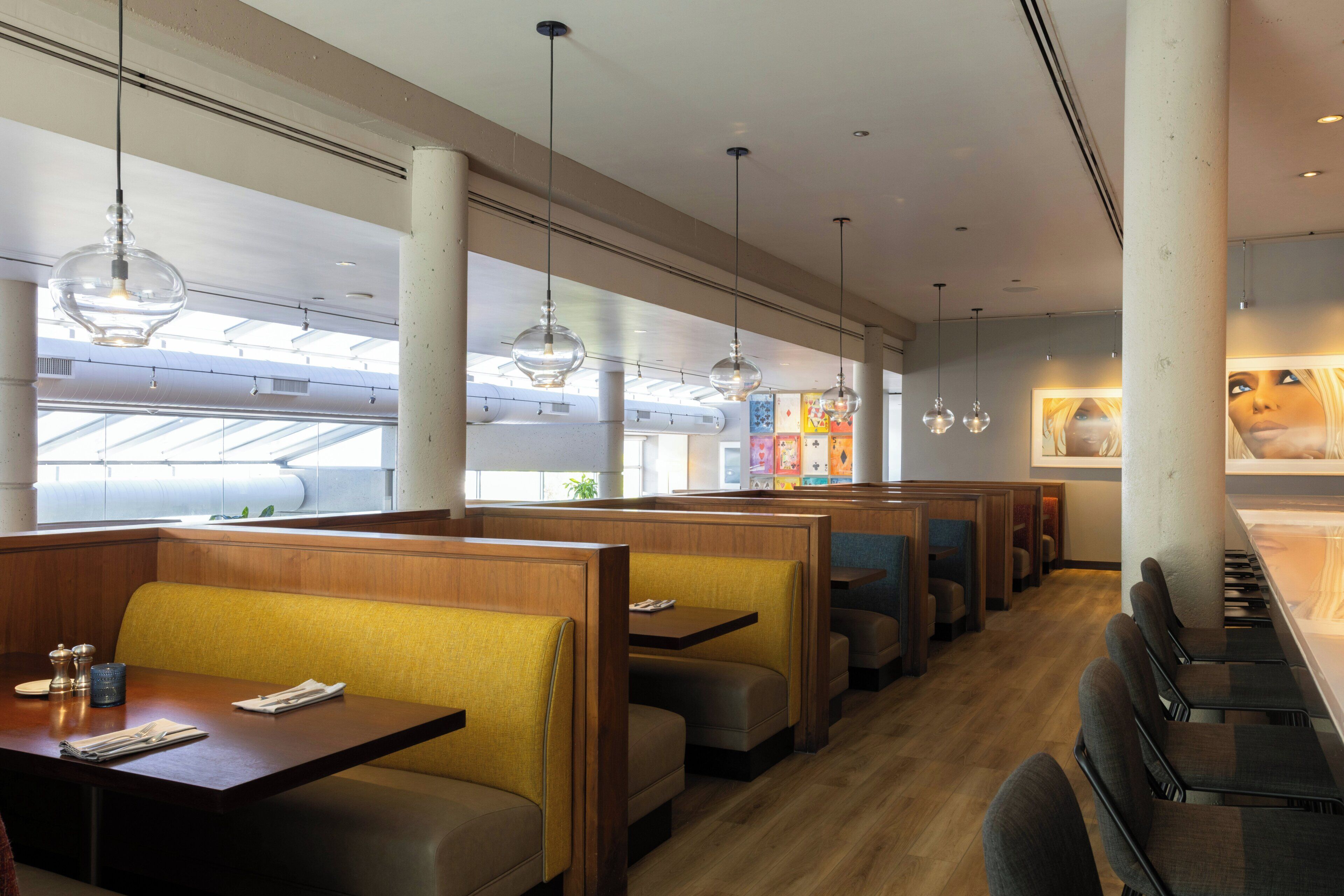 A restaurant interior with booth seating, pendant lighting, and a view of the sky through skylights.