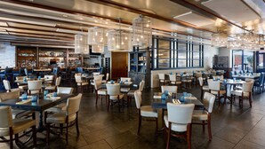 A spacious restaurant with multiple tables and chairs, a bar area, and large windows providing natural light. - The Alexandrian Old Town Alexandria, Autograph Collection (Alexandria)