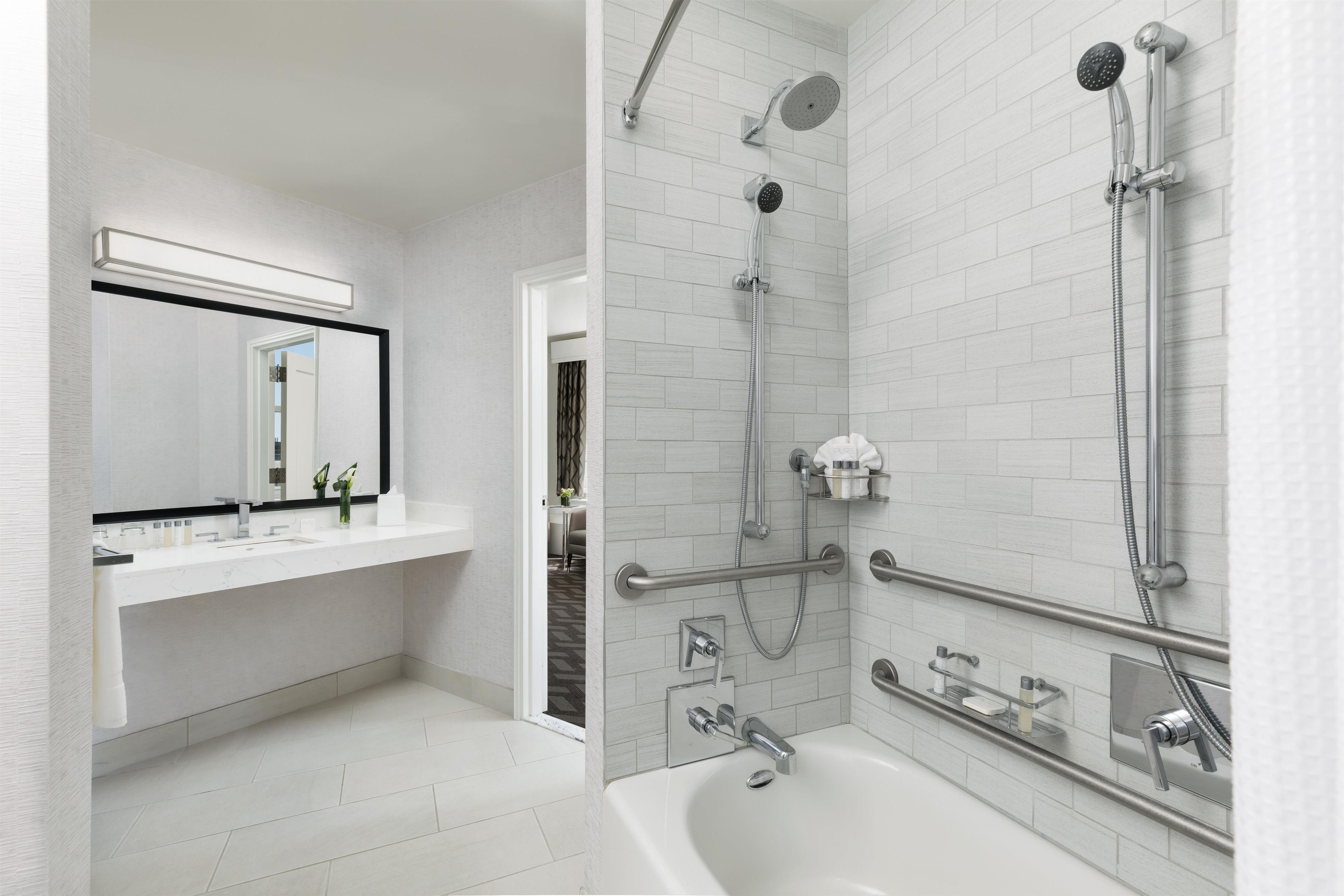 Ein modernes Badezimmer mit einer Badewanne, einer Dusche inklusive Handbrause und einem Waschtisch mit Spiegel.