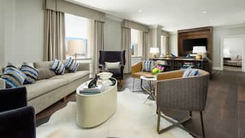 A modern hotel living room with a sofa, armchairs, a coffee table, and a TV.