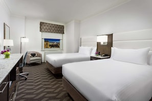 A hotel room with two beds, a desk with a chair, a window with a city view, and a patterned carpet. - Hilton Boston Park Plaza (Boston)