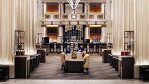 Eine geräumige Lobby mit einem prächtigen Kronleuchter, einem Empfangsbereich und einer Sitzecke mit Tisch und Stühlen.