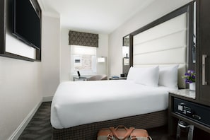 A hotel room with a large bed, a desk with a laptop, a chair, and a window with a view of the outside. - Hilton Boston Park Plaza (Boston)