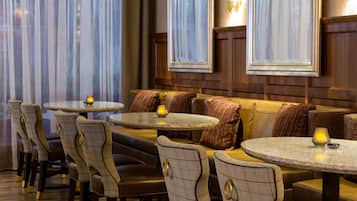 A restaurant with round tables and cushioned seating, featuring a warm ambiance and wooden paneling.