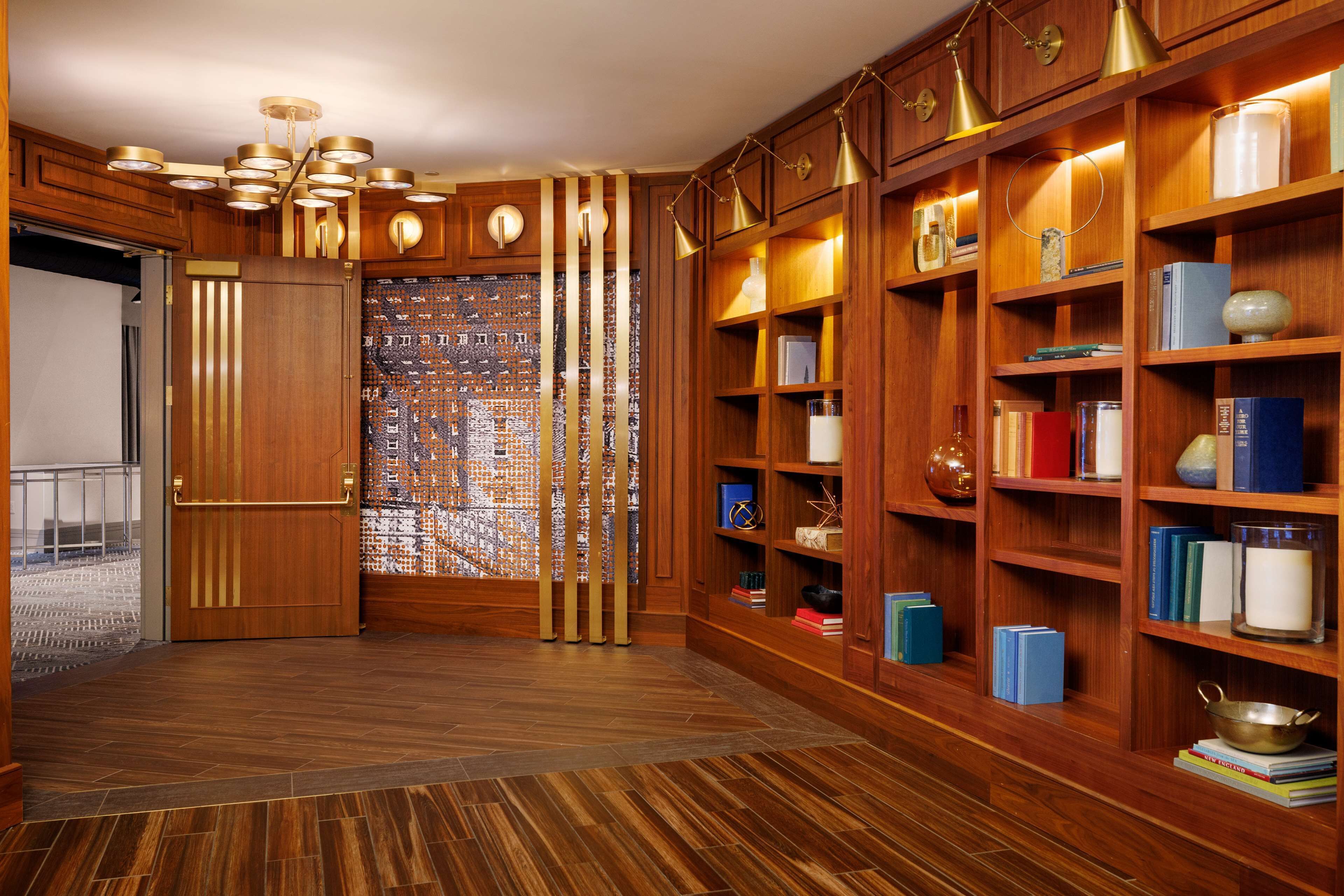 Una biblioteca con estanterías de madera, un papel tapiz decorativo y suelo de madera.