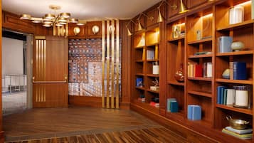 Una biblioteca con estanterías de madera, un papel tapiz decorativo y suelo de madera.