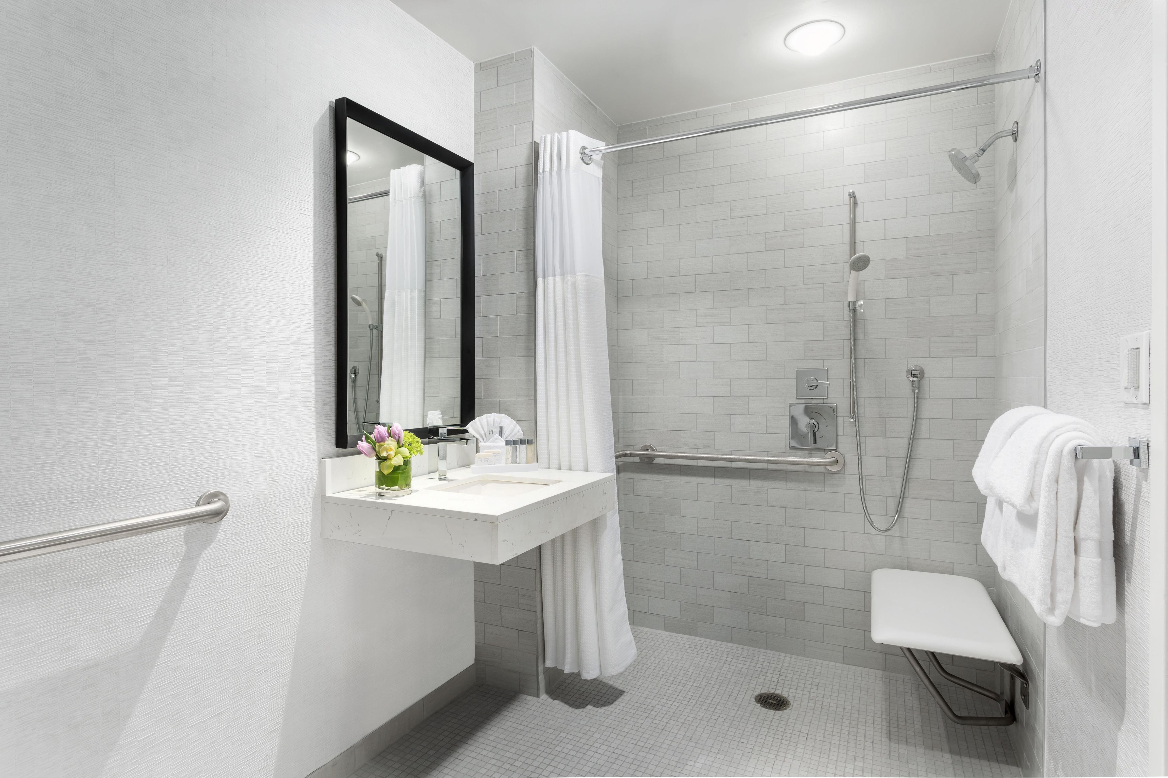 A modern bathroom with a white sink, mirror, and shower.
