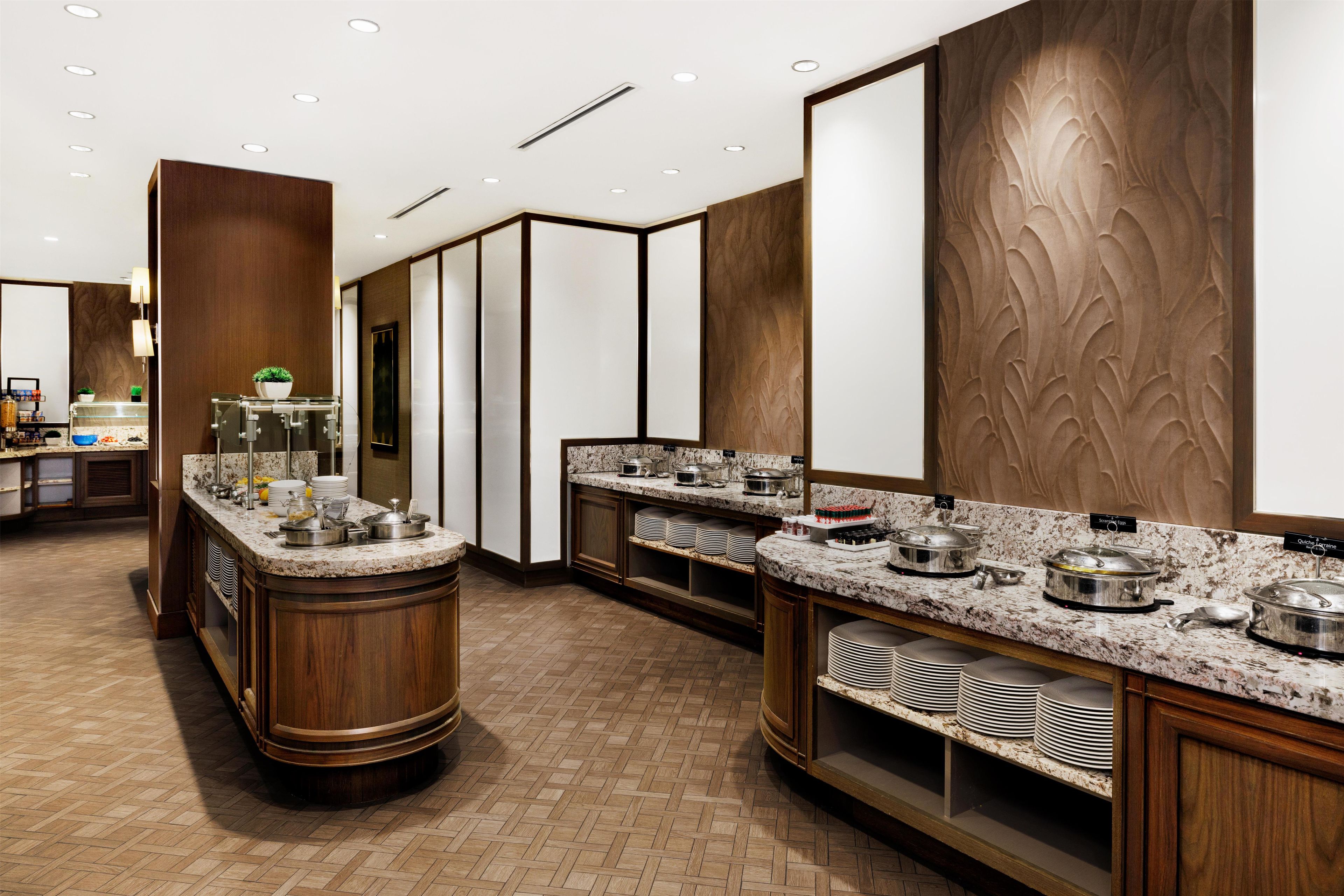 Een moderne hotelkeuken met een centraal eiland, een buffetopstelling en een visgraat houten vloer.