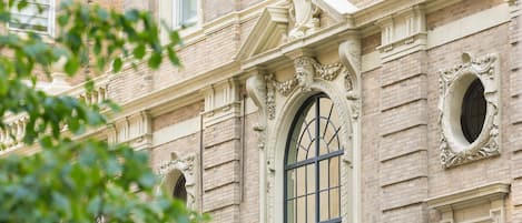 Fachada de edificio con detalles arquitectónicos ornamentales, incluyendo un gran ventanal en arco y labor de cantería decorativa.