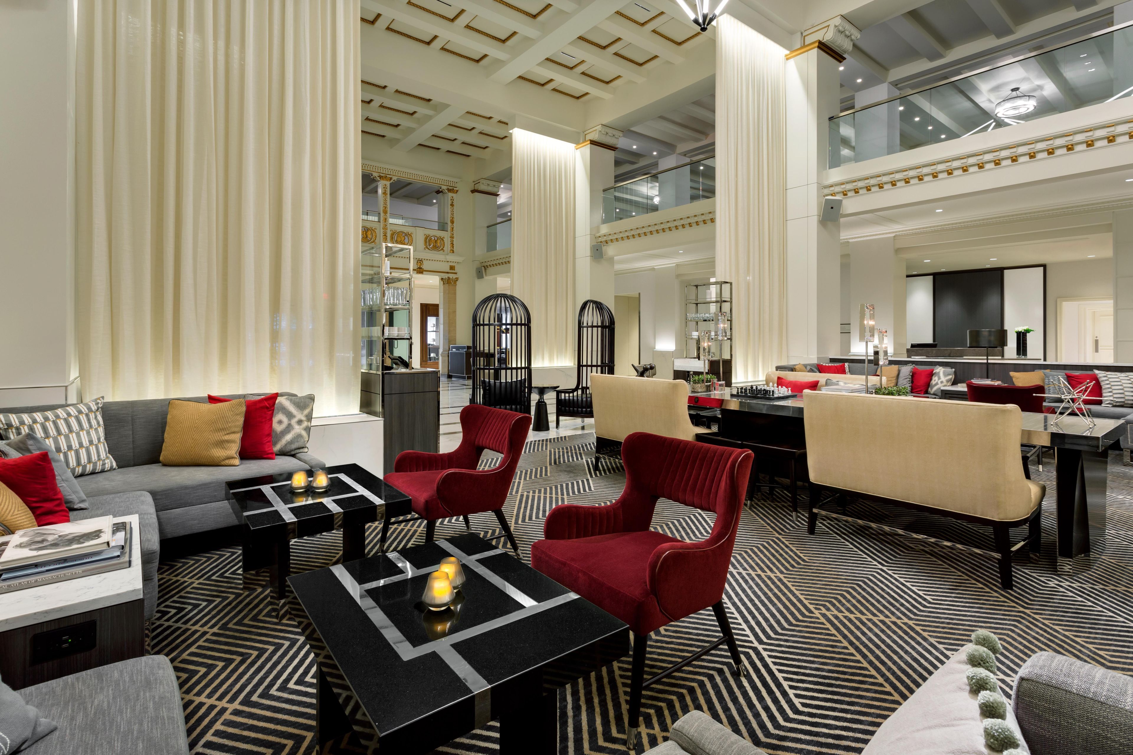 Un amplio salón con techo alto, muebles modernos y alfombra estampada.