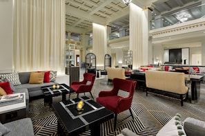 A spacious lounge area with a high ceiling, modern furniture, and a patterned carpet. - Hilton Boston Park Plaza (Boston)
