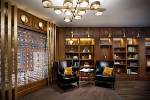 A library with bookshelves, two leather chairs, a patterned wall, and a ceiling light fixture. - Hilton Boston Park Plaza (Boston)