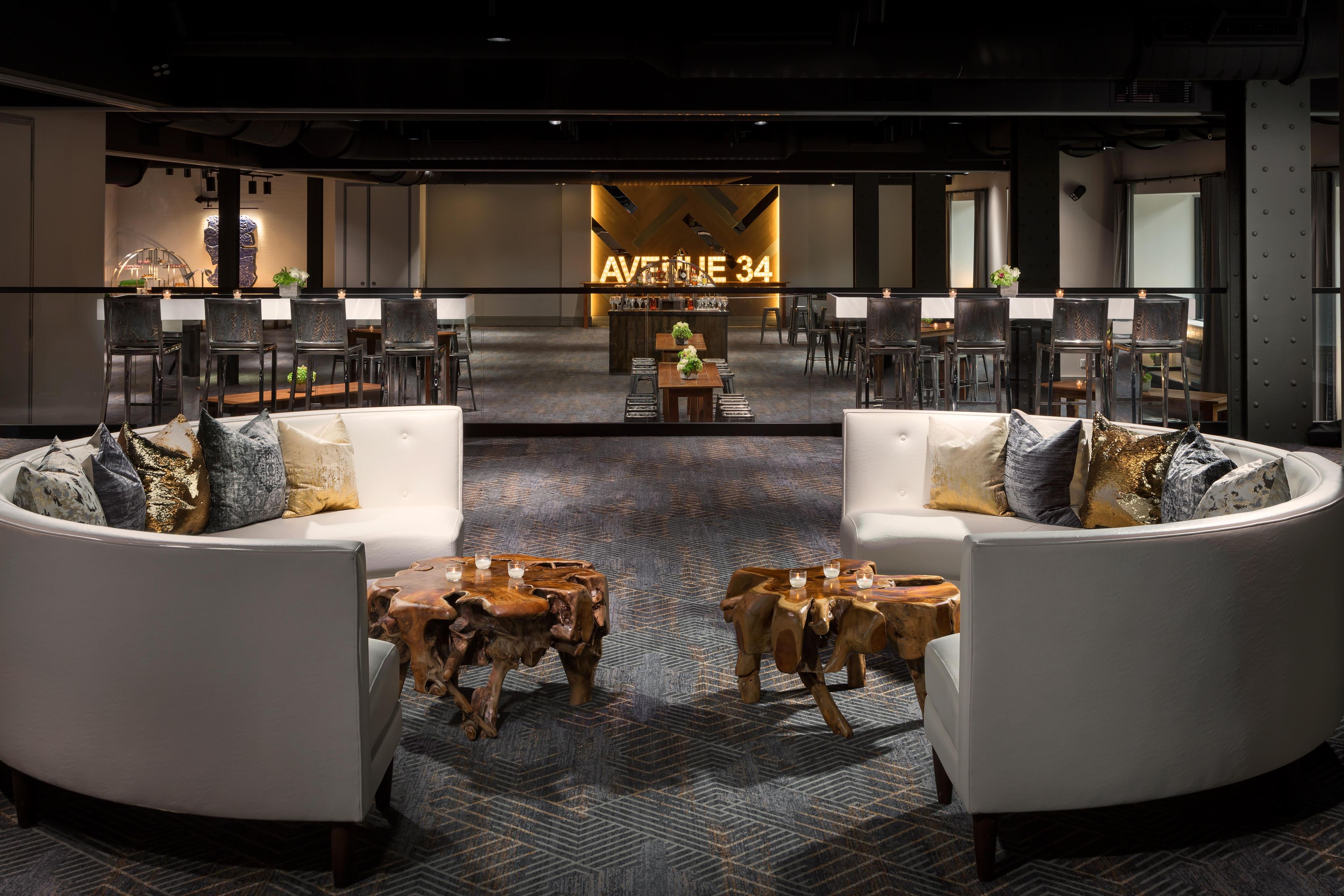 A modern lounge area with a bar, seating arrangements, and a patterned carpet.
