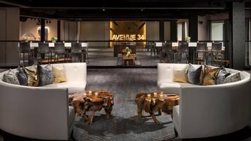 A modern lounge area with a bar, seating arrangements, and a patterned carpet.