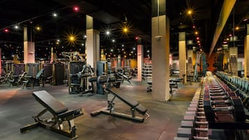 A gym with various exercise equipment, including benches and weight machines, under bright overhead lighting.