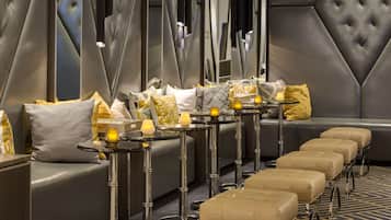 A modern lounge area with leather sofas, a long bench, and a row of small tables with candles.