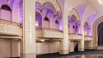 Un salón imponente con arcos decorativos y un balcón con barandilla ornamental.