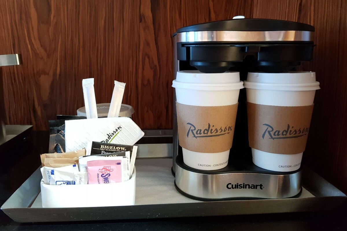 A coffee station with two branded cups, a coffee maker, and a tissue box.