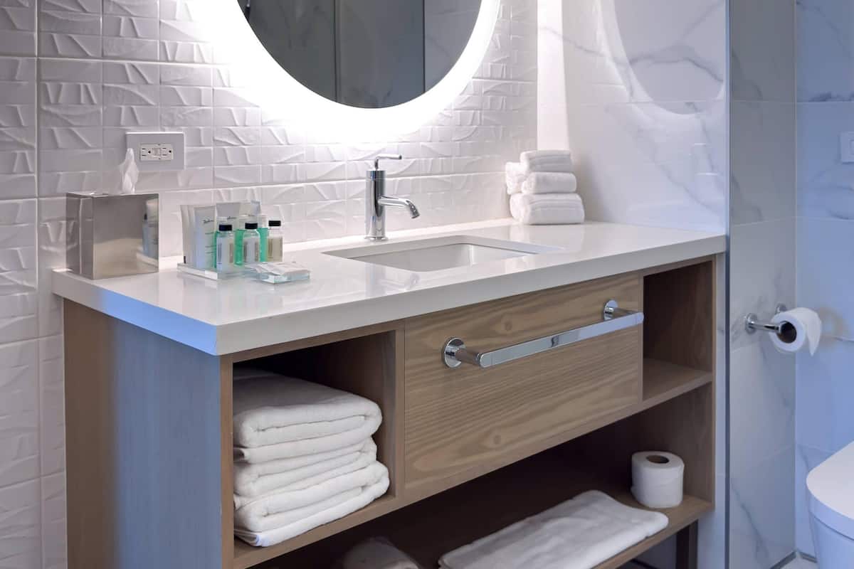 A bathroom with a white sink, a mirror, and a towel rack.