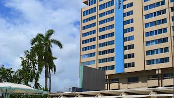 A hotel with a large pool, palm trees, and a clear blue sky.
