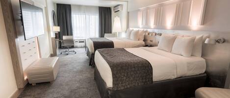 Una habitación de hotel con dos camas, un escritorio, una silla, un televisor y una ventana con cortinas.