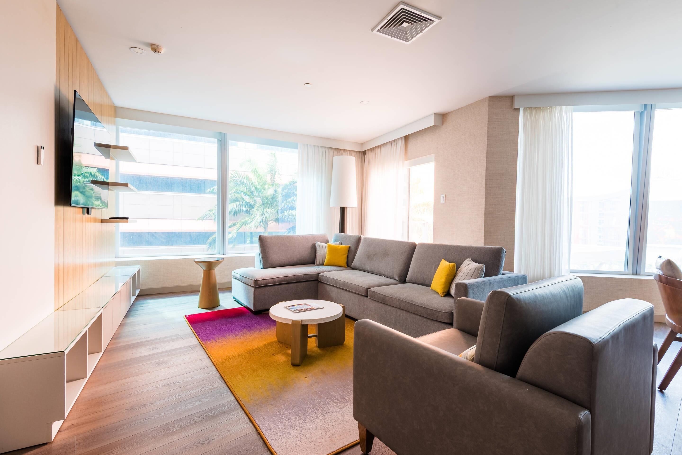 Una sala de estar moderna con un sofá modular, una mesa de centro redonda y un televisor de pantalla plana montado en la pared.