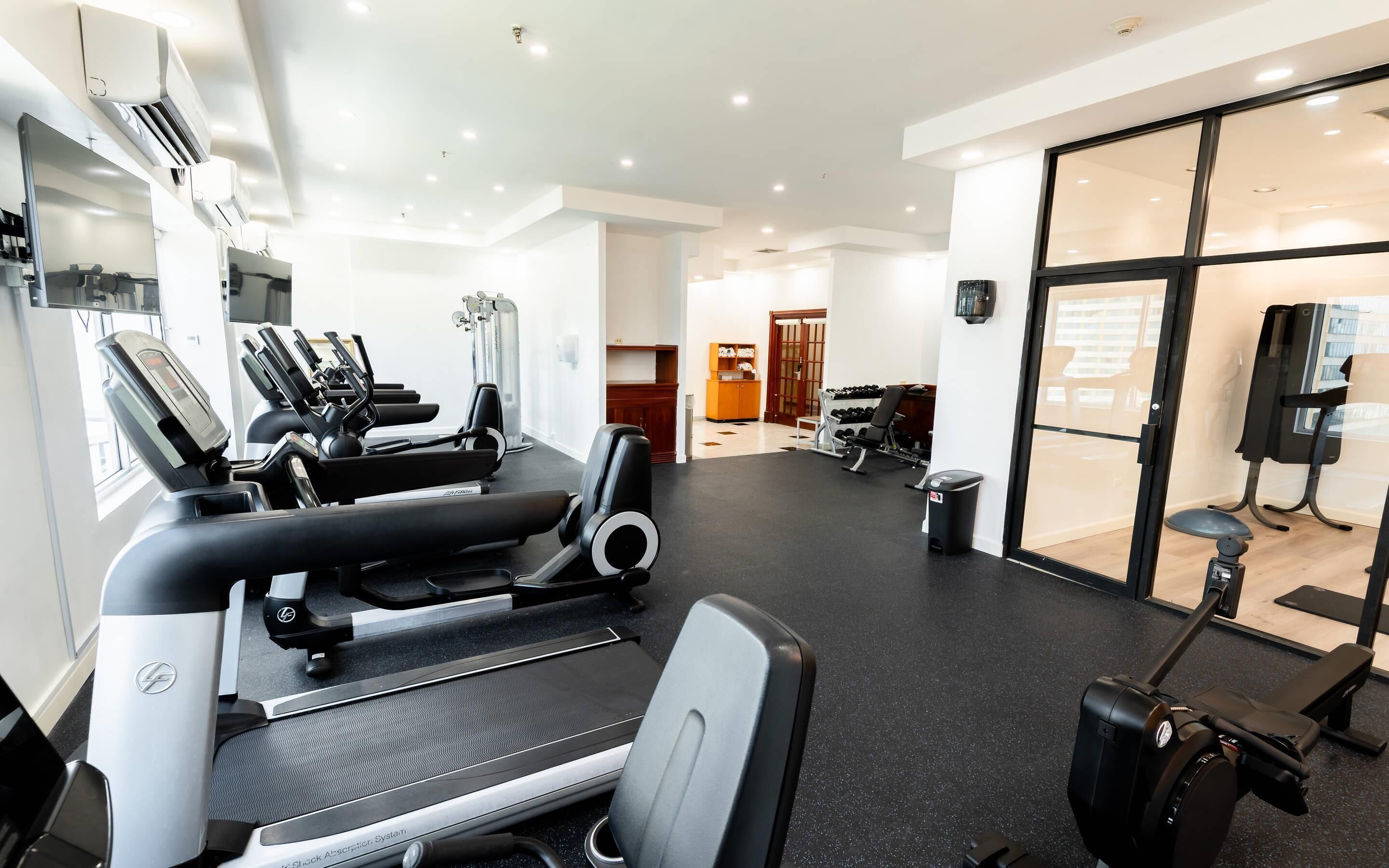 A gym with treadmills, weight machines, and a rowing machine.