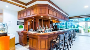 A bar area with a wooden counter, bar stools, and a menu board.