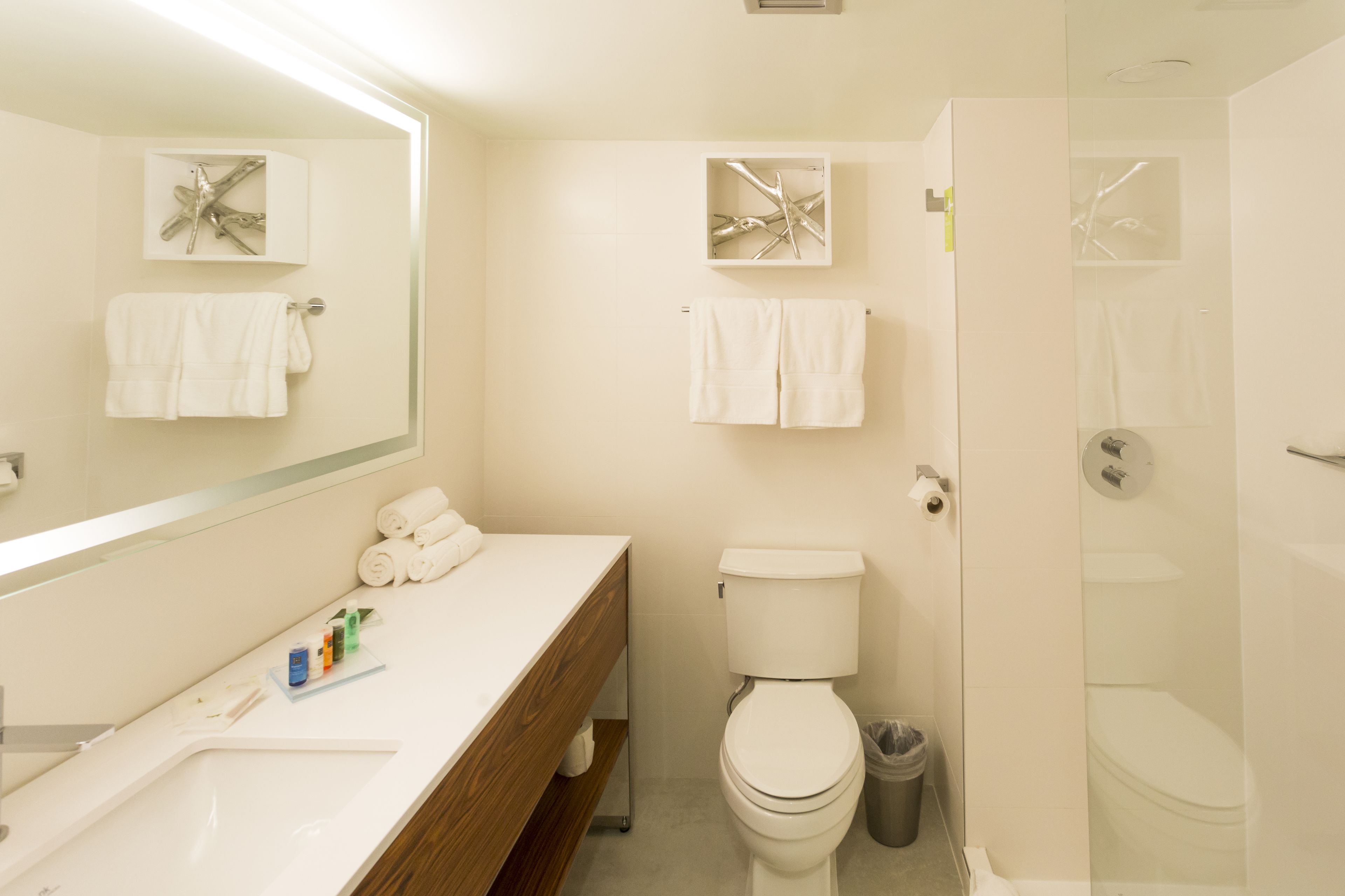 A modern bathroom with a wooden vanity, a toilet, and a shower.