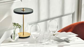 Una mesa de comedor dispuesta con un jarrón de flores, un vaso y una cuchara.