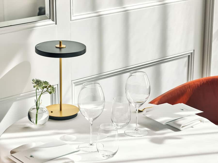 Una mesa de comedor dispuesta con un jarrón de flores, un vaso y una cuchara.