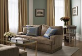 A living room with a sofa, coffee table, and a vase of flowers.