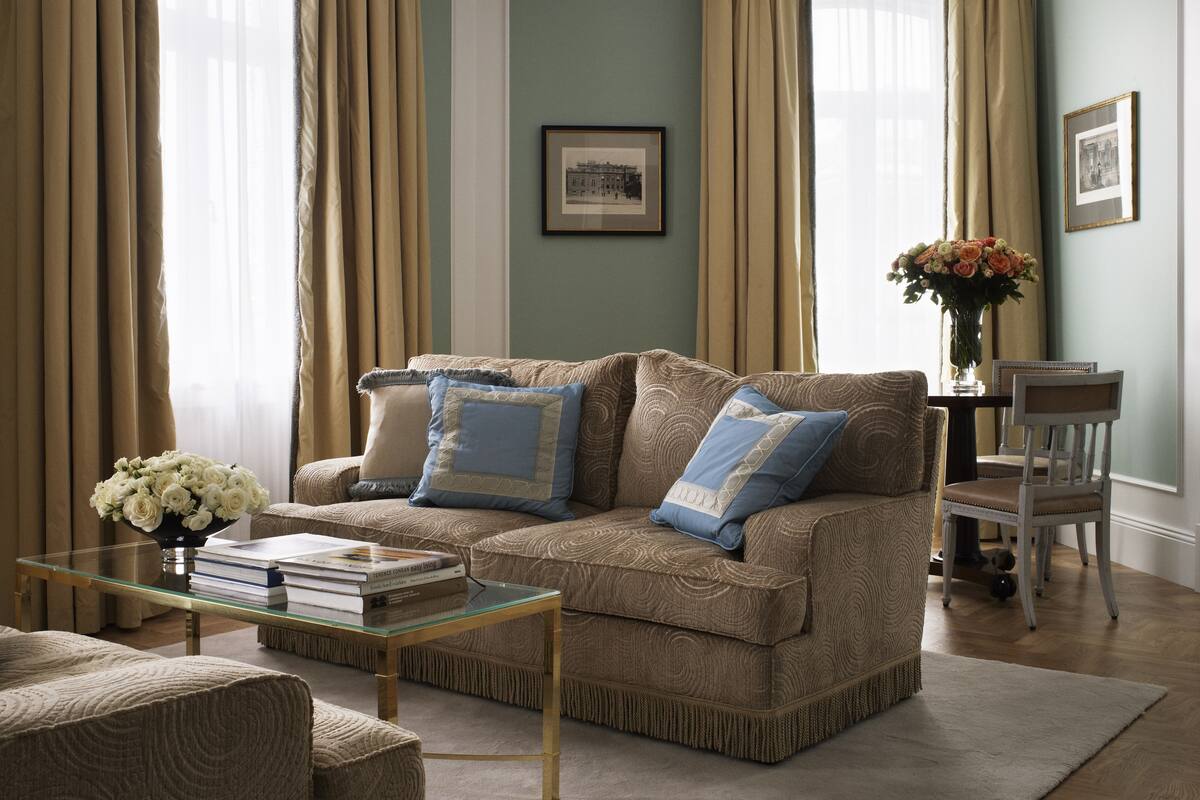 A living room with a sofa, coffee table, and a vase of flowers.