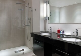 A modern bathroom with two sinks, a glass shower enclosure, and a large mirror.
