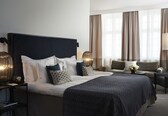 A modern hotel room with a large bed, a sofa, and a desk.