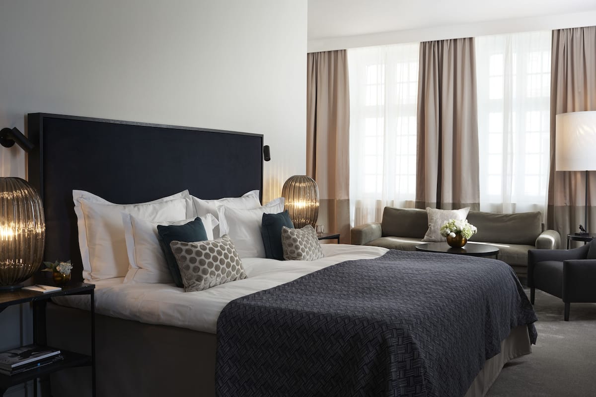 A modern hotel room with a large bed, a sofa, and a desk.