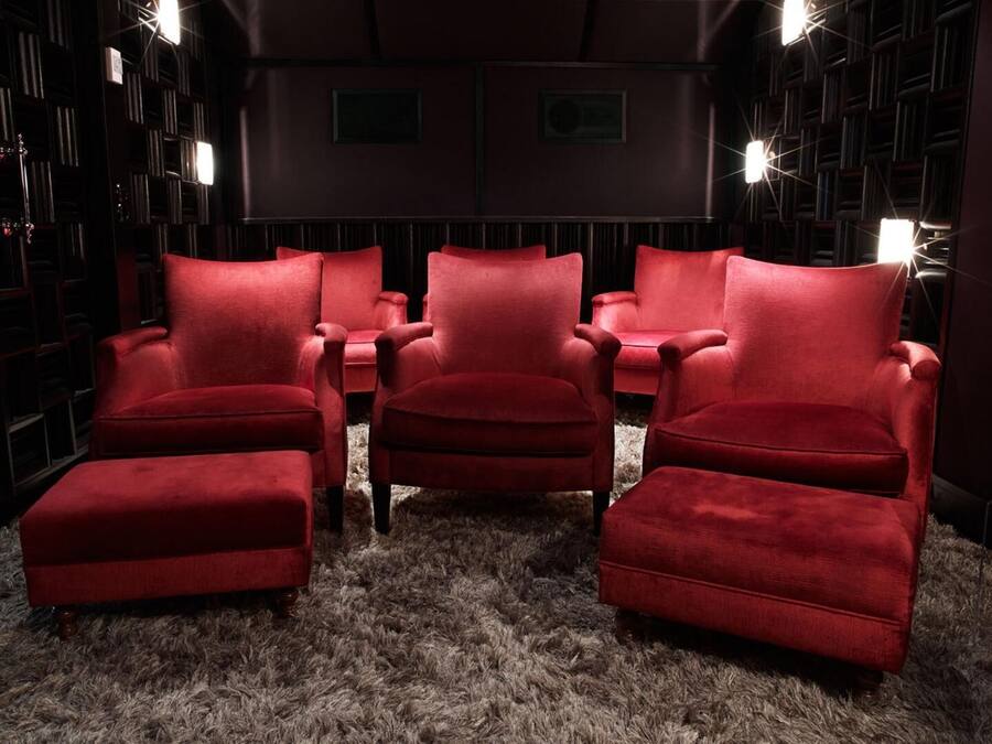 A cozy room with plush red armchairs and a fluffy rug, surrounded by bookshelves.