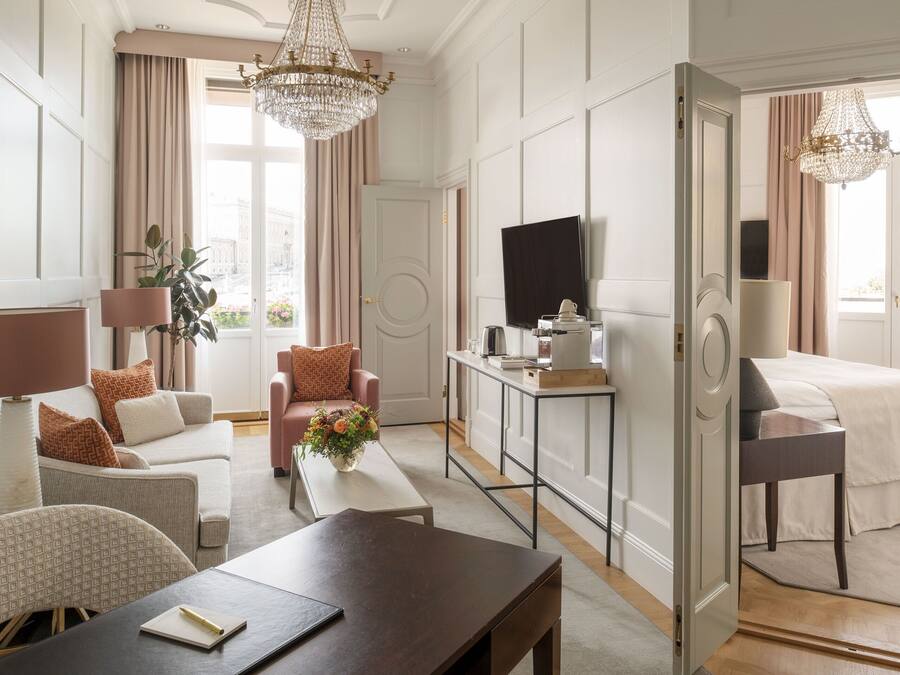 A hotel room with a bed, a desk, a chair, a television, and a large window with curtains.
