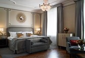 A well-appointed bedroom with a large bed, a sofa, a desk, and a chandelier.