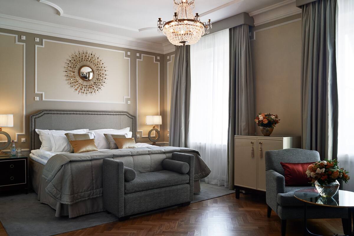 A well-appointed bedroom with a large bed, a sofa, a desk, and a chandelier.